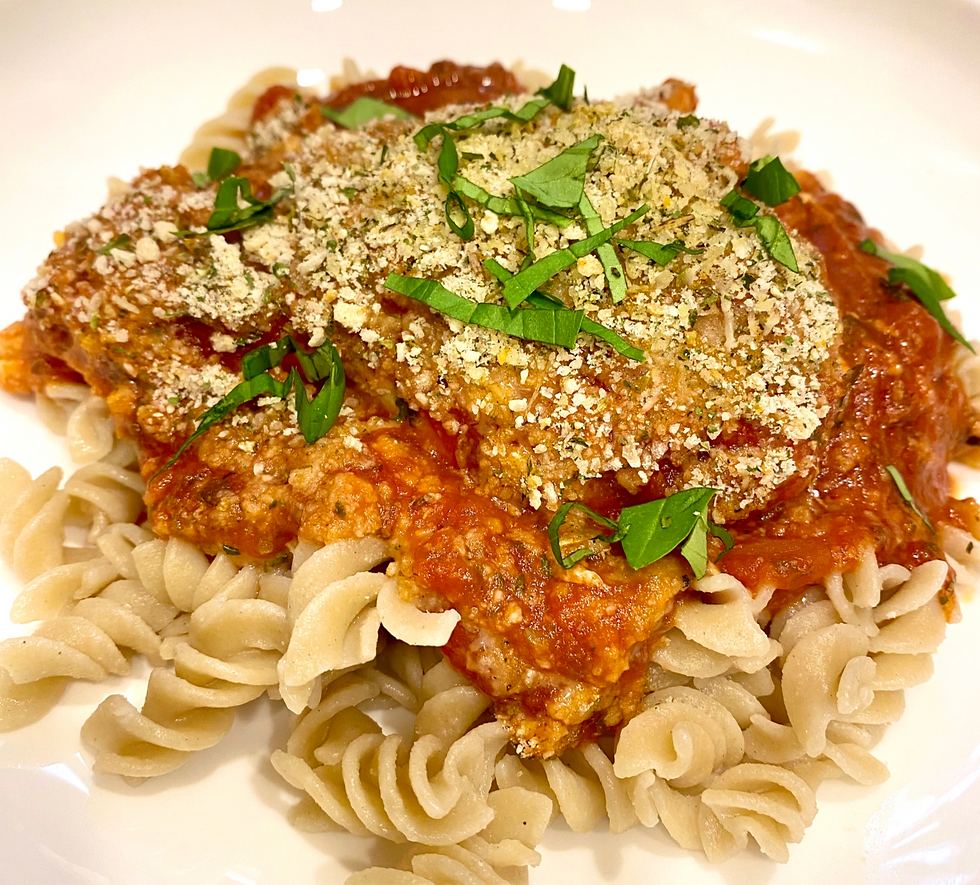 Easy weeknight chicken parmesan served on a plate with gluten free pasta and fresh basil on top