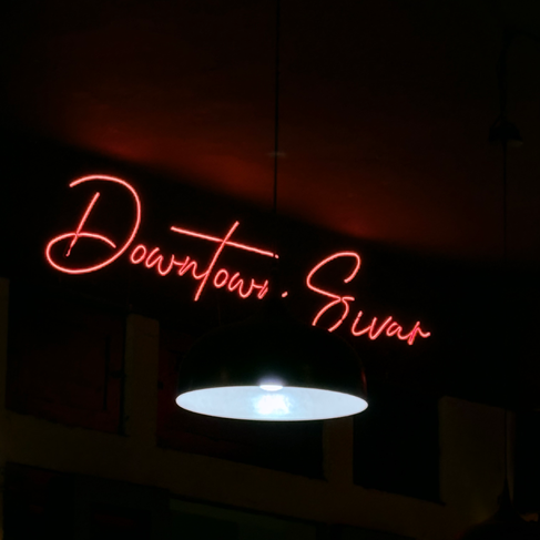 A red neon sign at a bar that says "Downtown Sivar".