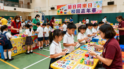 jimeng-2025-11-25-8417-香港小學生參加學校舉辦的節日嘉年華活動,在操場或禮堂裡設有多個攤位遊戲和小手作區...