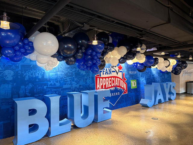 Navy, white and blue balloon garland hanging above oversized BLUE JAYS letters at a Toronto Blue Jays Fan Appreciation event