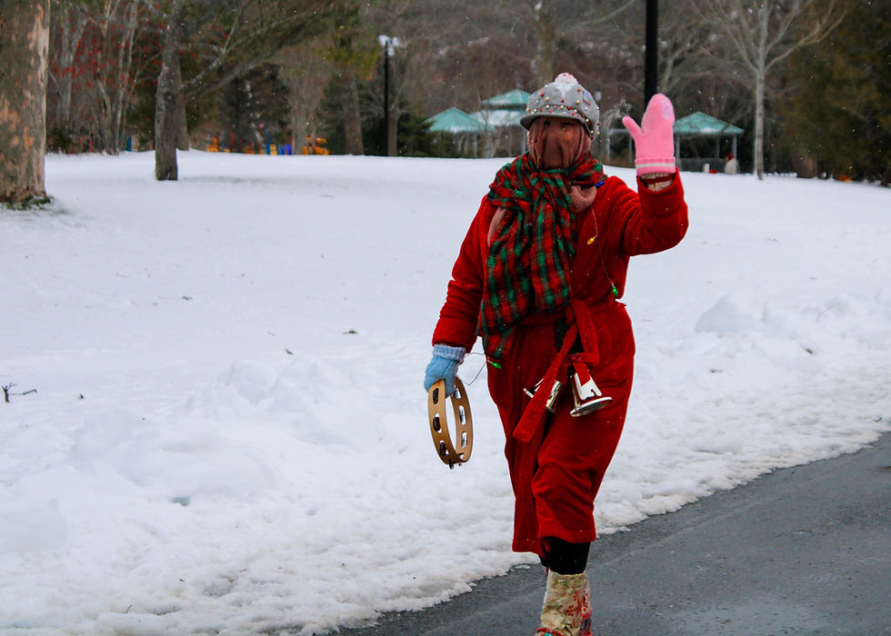 This Mummer, bells attached to her red housecoat and wearing odd colored mitts, waves and shakes her tambourine as she walks by.
