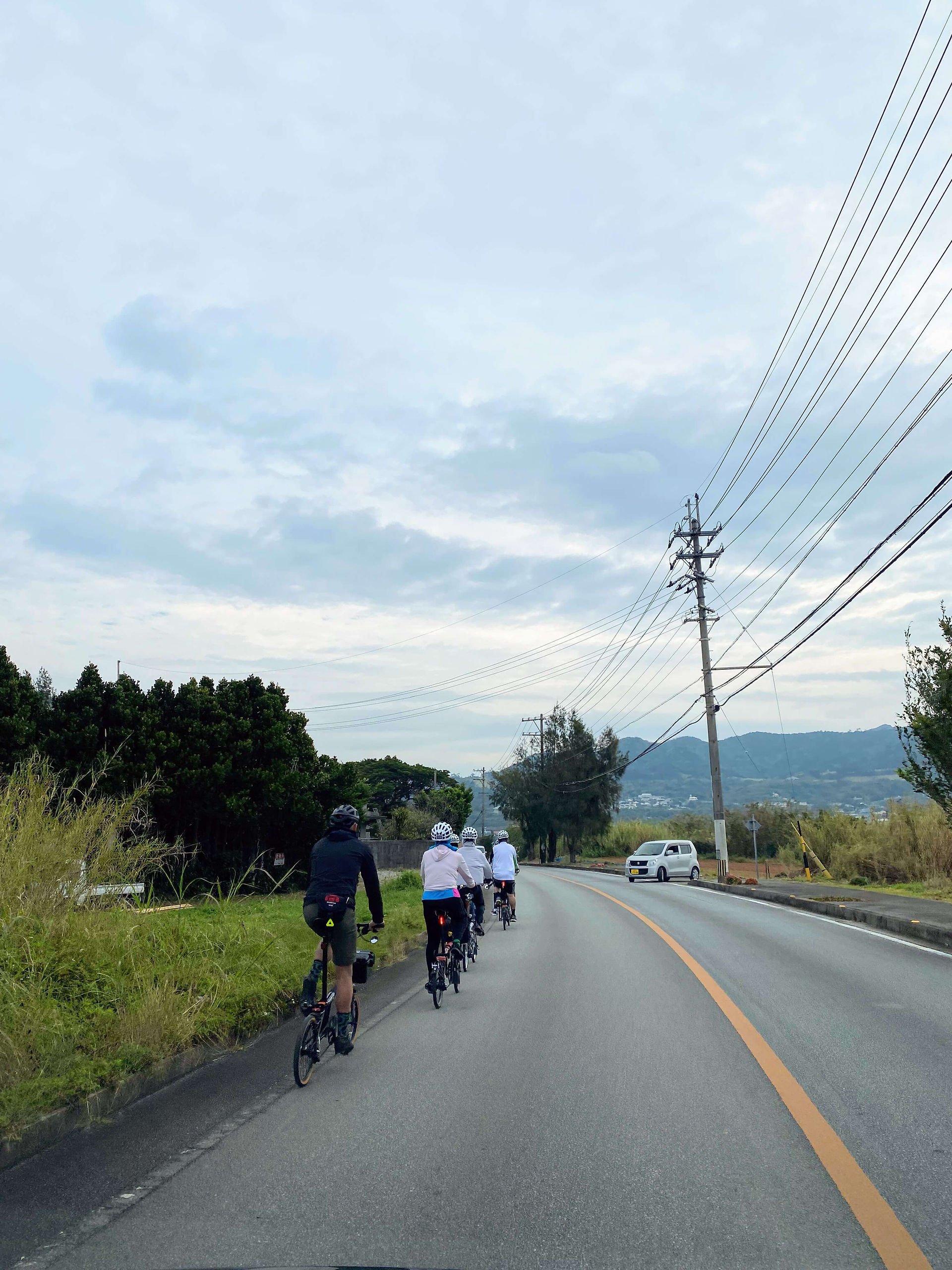 Tour participants riding in Okinawa on a long road