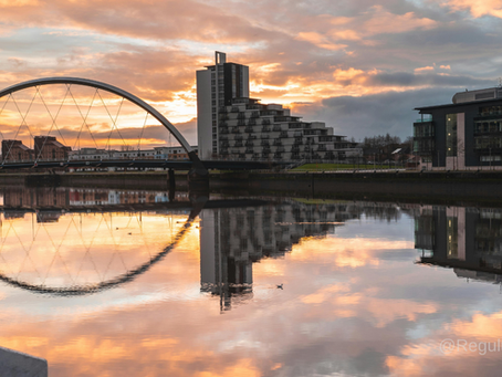 Glasgow bridge, in the city centre with luxury buildings reflecting on the river, with the sunsetting 