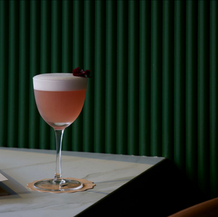 Pink cocktail with foam and flower garnish