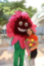 Woman holding flowers posing with a pink floral mascot.
