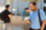 Man in a blue shirt holding pink roses outdoors.