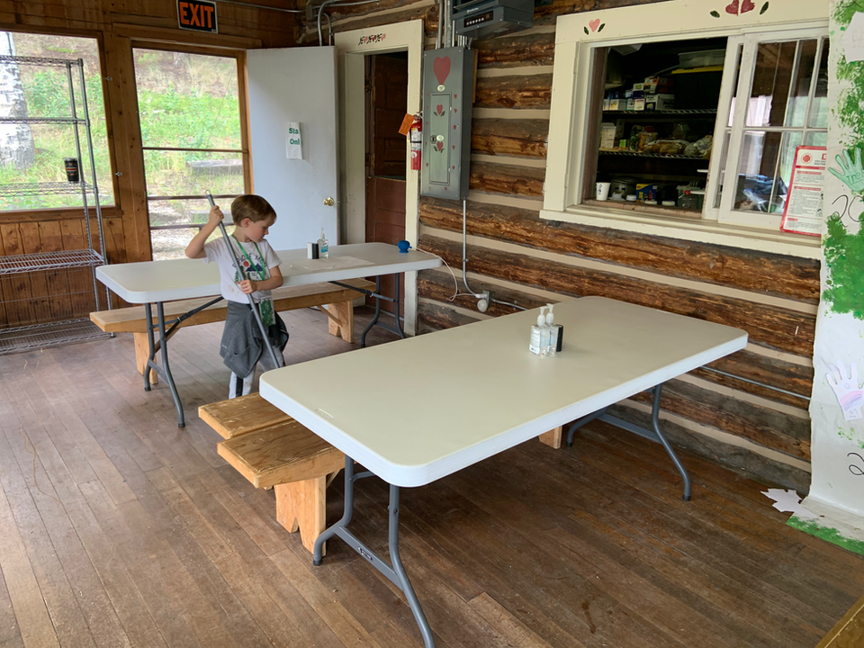 Young boy sweeping under a table in a cafeteria