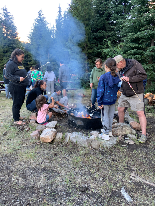 group of people around a campfire roasting marshmallows