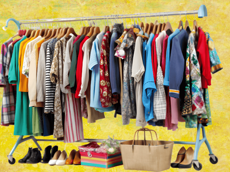 Clothes on hangers, colorful shirts and dresses on a rack against a yellow background. Shoes and bags on the floor. Bright and lively mood.