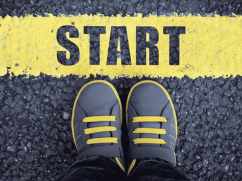 Blue shoes with yellow laces stand on asphalt, facing a bold yellow line with the word "START." Mood suggests anticipation.