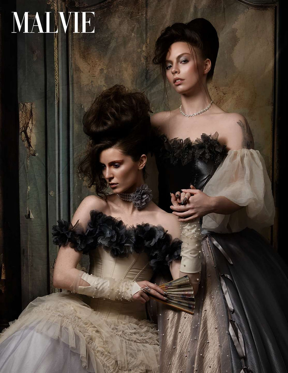 The two models together, one in ivory leaning against the other in pewter satin, holding a fan