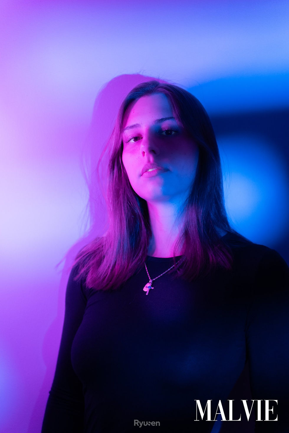 Elodie Lassus lit in pink and blue, looking into the camera