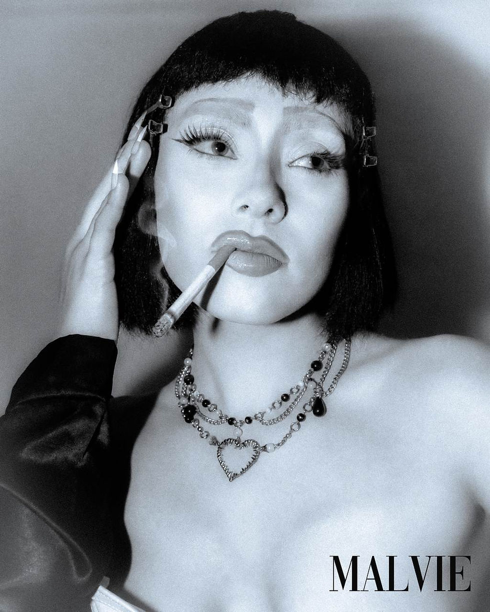 Black and white portrait of the model with a cigarette, her hand at her temple