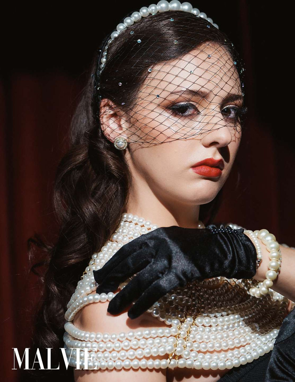 Model in a net veil looking over a black satin gloved hand, pearl bracelets on her wrist