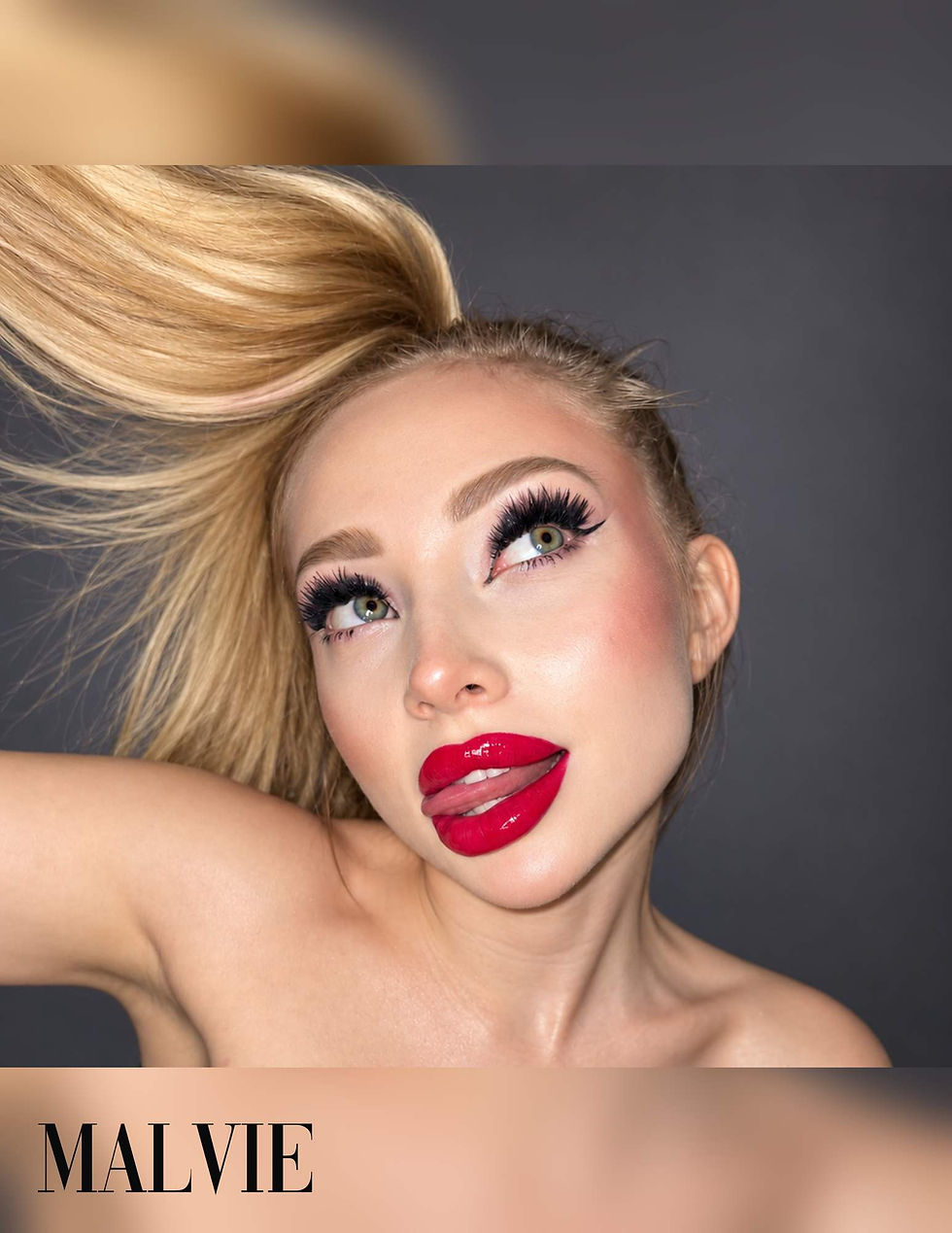 Close-up of the model looking up, her blonde ponytail flying, glossy red lips