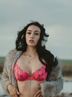 Kira May in a hot pink lace set and a grey faux-fur coat on a windswept beach – Hot Pink by Naveen Kumar Gadela for MALVIE Magazine