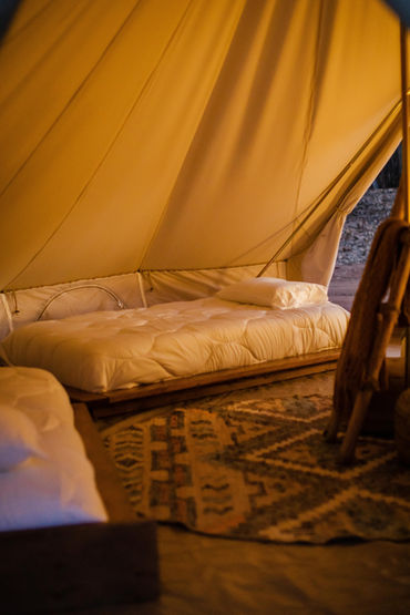 Glamping tent in Utah at Cave Lakes with twin beds, a wooden chair, and a patterned rug.