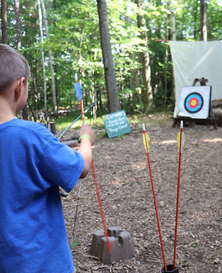 A young camper noks an arrow on his bow on the archery range