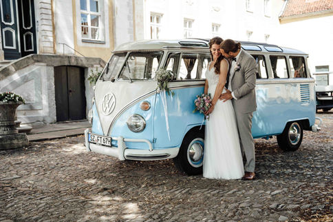 Braut und Bräutigam werden vor einem VW Beetle fotografiert