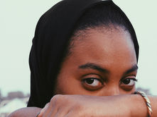 woman in black hijab covering her face with her hand