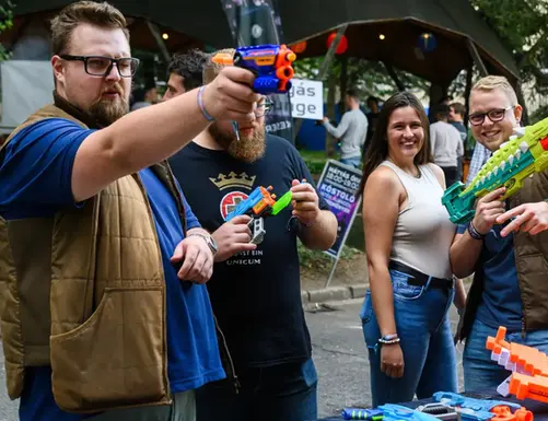 Felnőttek céloznak a Nerf céllövöldében egy céges rendezvényen.