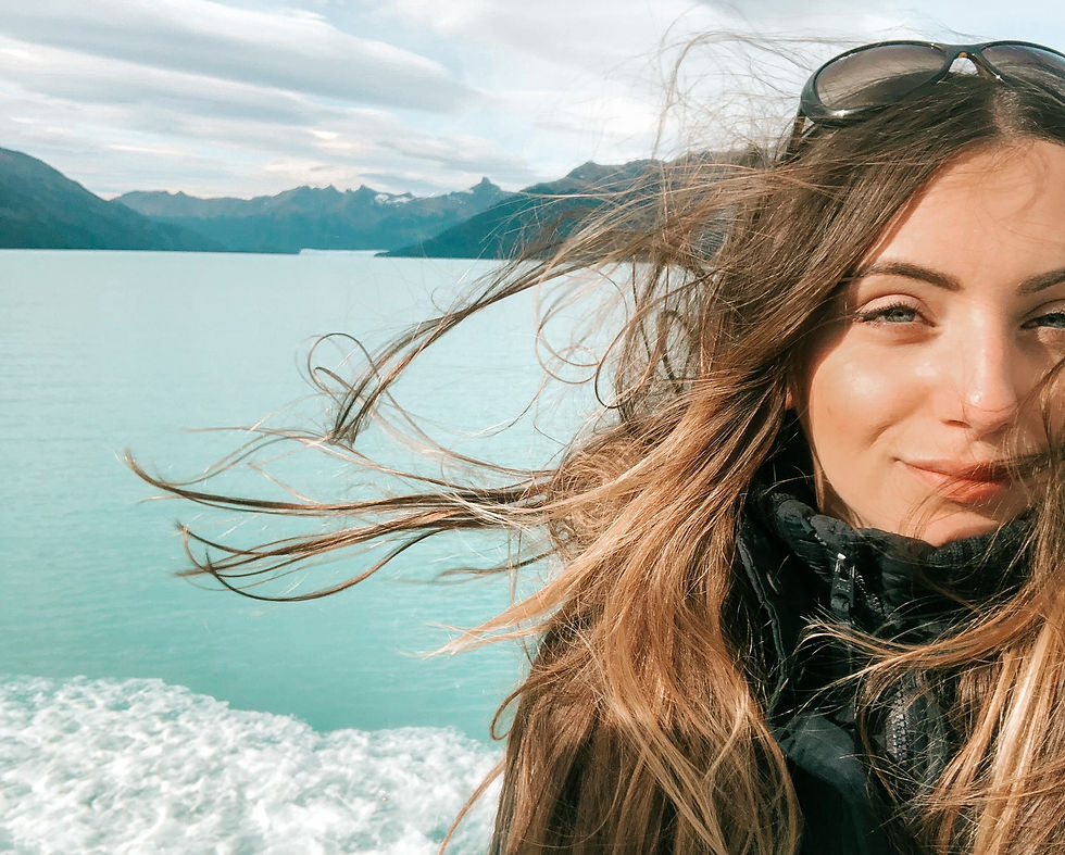 Selfie of a woman with long hair with turquoise glacier water in the back, at Perito Moreno in Argentina