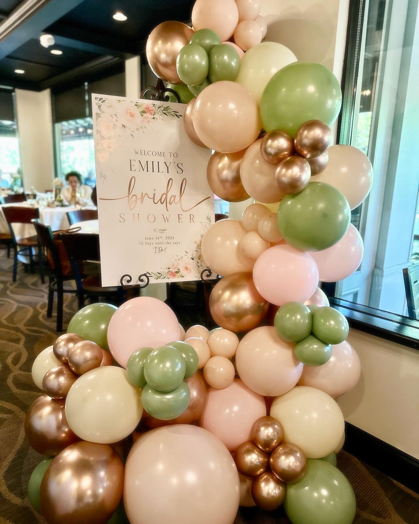 Balloon garland wrap around a board saying "welcome to bridal shower", beige, pink, green and gold colors