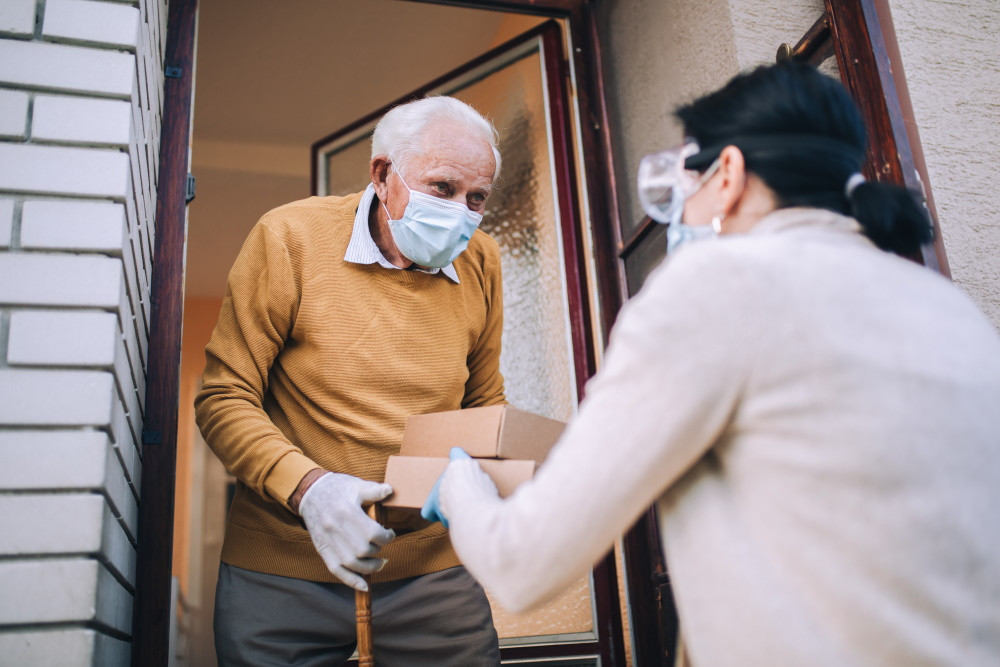 senior man with mask accepting delivery