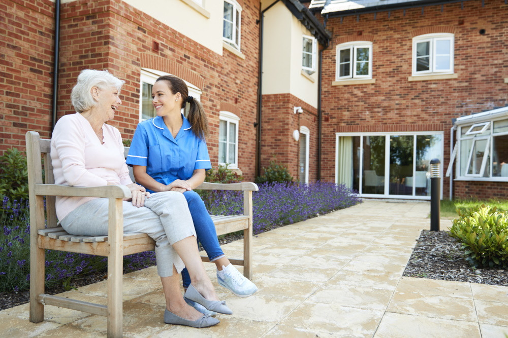 assisted living facility resident sitting on bench with staff member