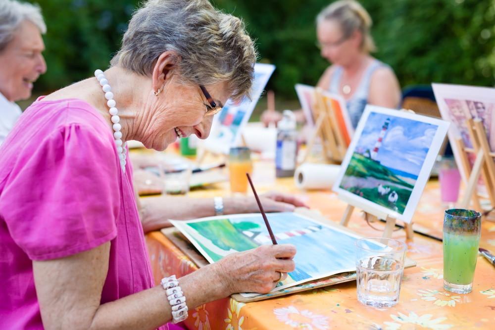 senior community resident painting with a group