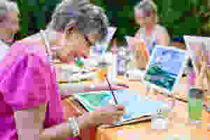 senior community resident painting with a group