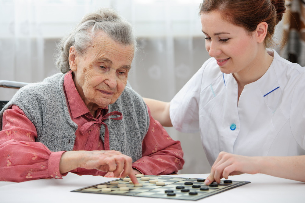 senior woman playing checkers with assisted living nurse