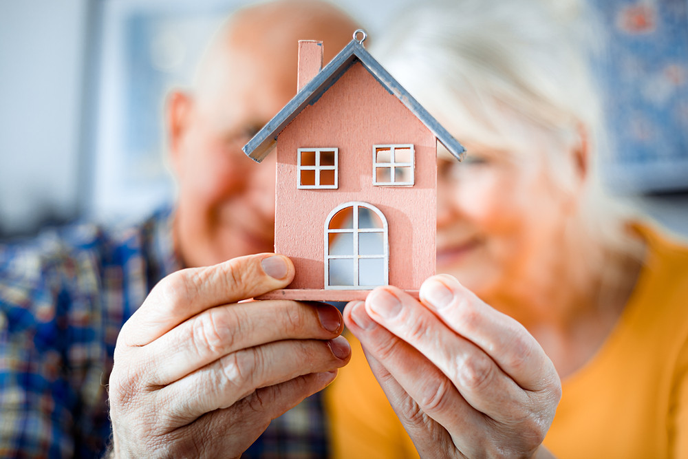 senior couple holding a mini home model