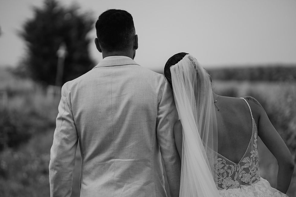 Photo de dos d’un couple de mariés marchant main dans la main, la mariée pose sa tête sur l’épaule du marié