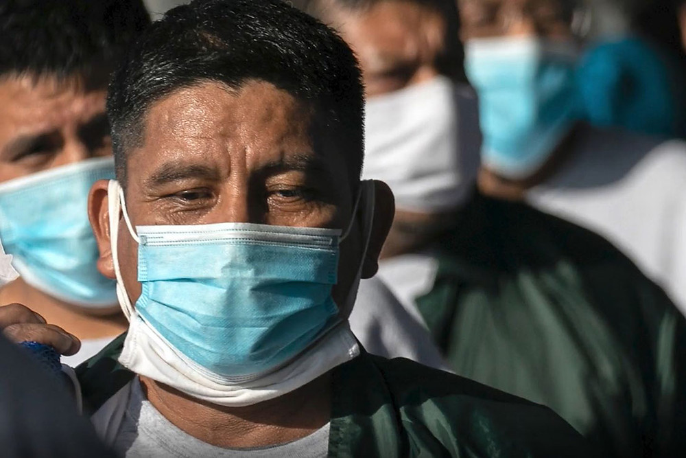 A group of men seeking asylum who have been placed in ICE detention wear COVID-19 prevention masks.