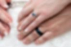 Hand in hand we see their wedding rings.