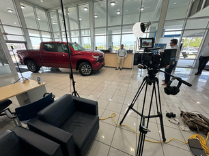 Filming car dealership videos and purchasing a new car.