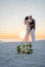 Kissing on the beach, a newly wed couple enjoy a sunset kiss.