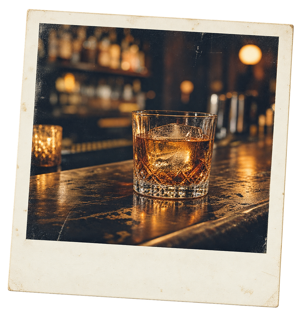 A single amber drink on a worn bar counter with warm bokeh.