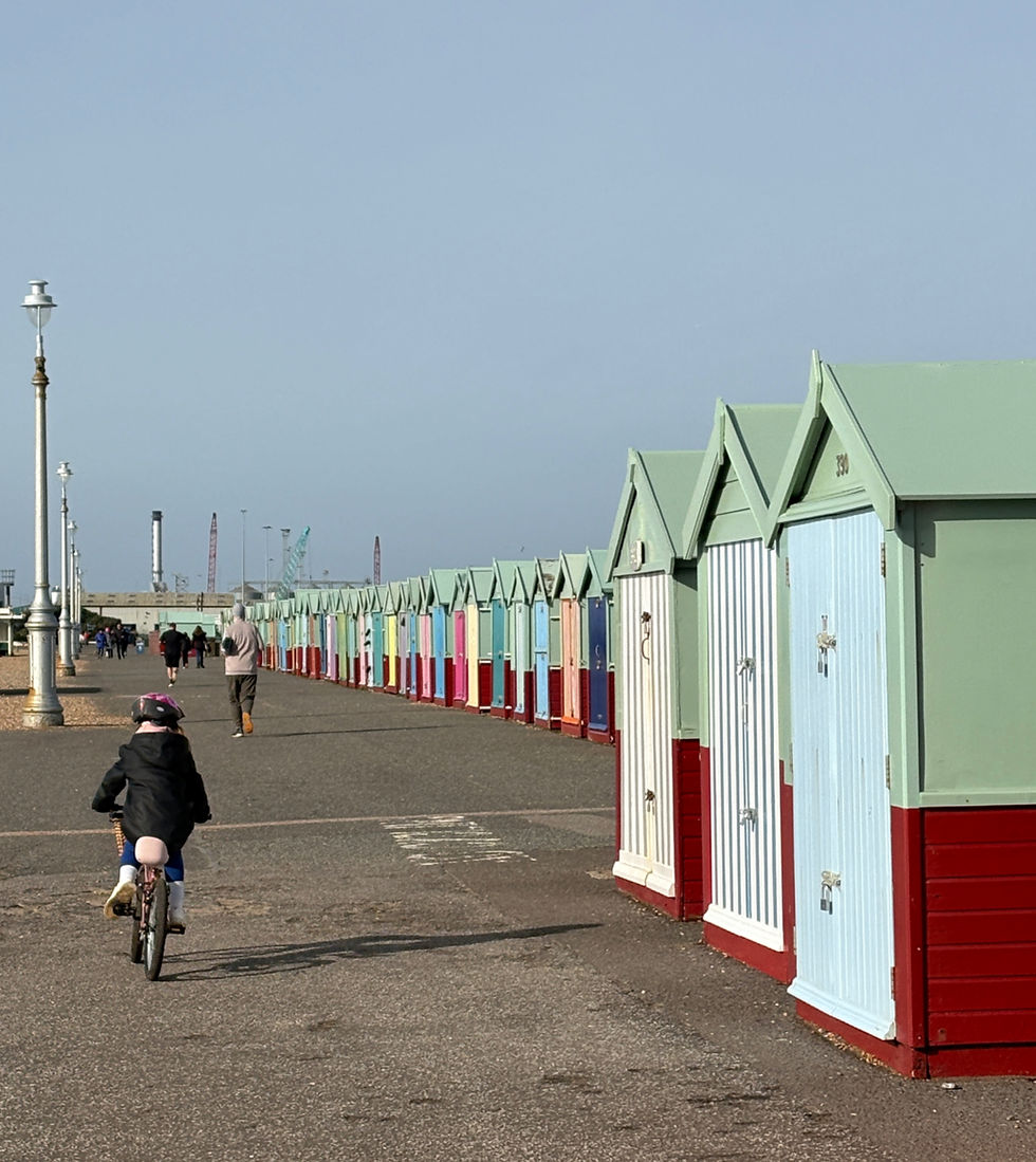 Image of a young girl jumping off of a wall onto a pebbly beach, blue skies