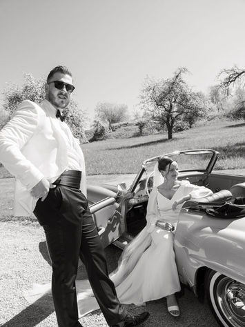 Black and white wedding photo of bride and groom with a vintage Mercedes during their elegant countryside wedding at Gut Aichet Bavaria.