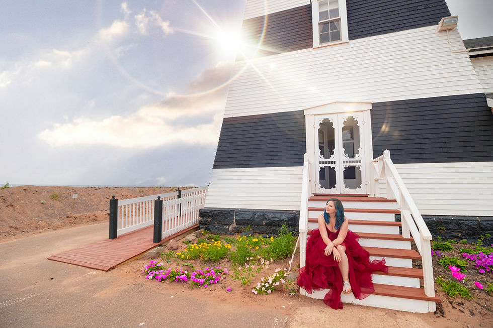 girl in beautiful red dress sitting on a lighthouse by the beach with the sun shining