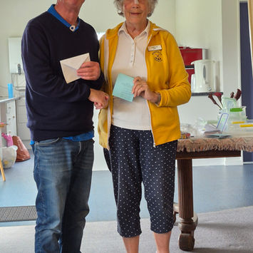 Man hands envelope to woman in yellow jacket