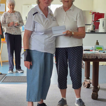 Two women, one presenting a document to the other at an event