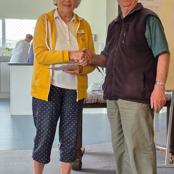 Woman shaking hands with man, holding award