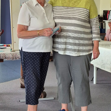 Two smiling women, one holding a card