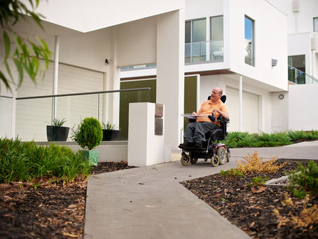 Man in an electric wheelchair outside his home
