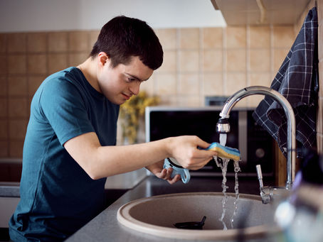 Man with down syndrome washing dishes in the kitchen.