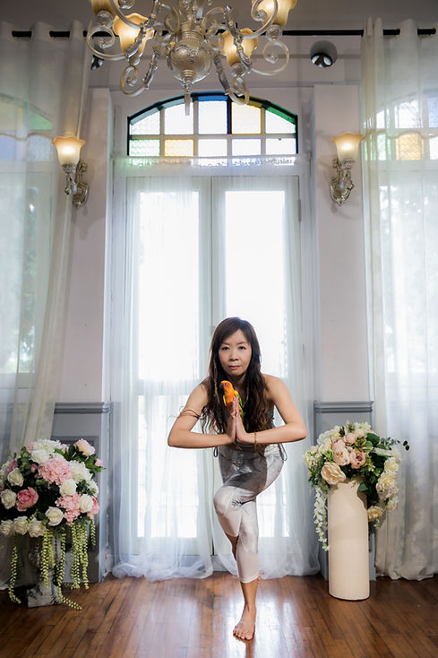 Amy Lim  practicing gentle yoga with her sun conure in a Singapore shophouse studio 