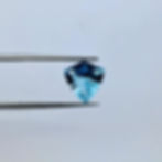 Video of the main gemstone, a shield cut aquamarine, held by a tweezer with all sides visible.